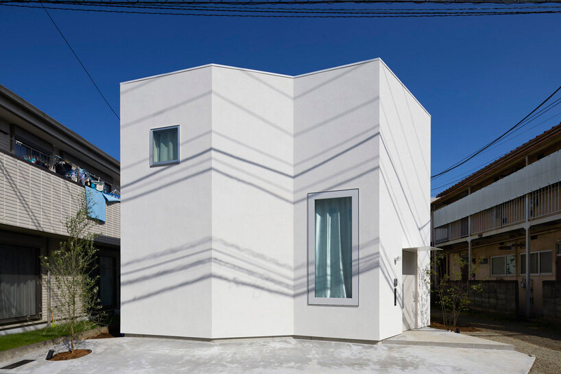 japanese residence by airhouse conceals minimalist interior of slanted floors and walls