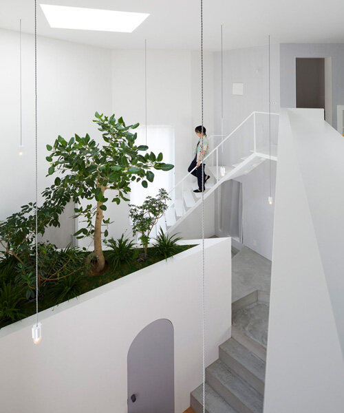 japanese residence by airhouse encloses minimalist interior of slanted floors and walls