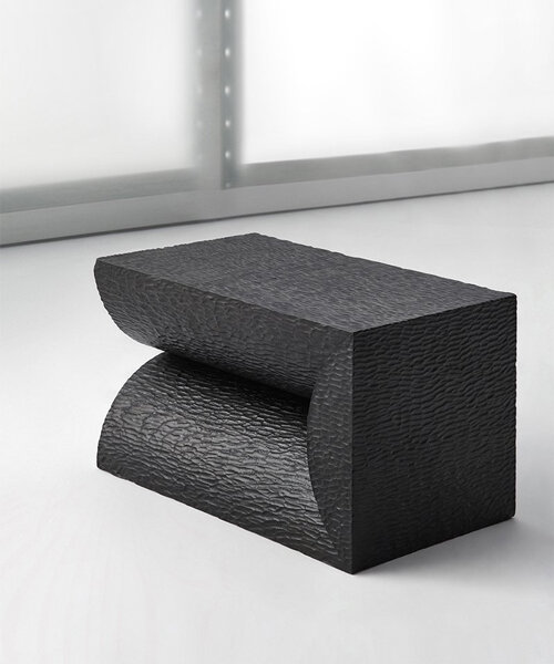 black monolithic furniture embraces organic semi-cylindrical forms + raw wood log textures