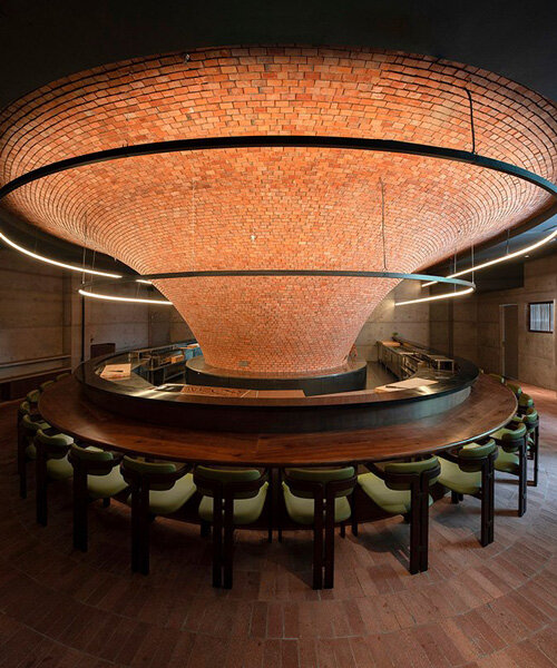 bar-like dining table encircles imposing raw brick funnel at yakitori restaurant in china