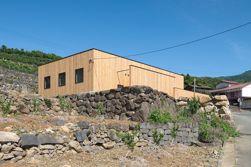 'house in tensui' emerges as a multi-layered wooden volume amid terraced fields in japan