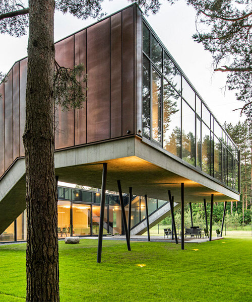 copper-clad zigzag house by g.natkevicius & partners hovers above pine forest in lithuania