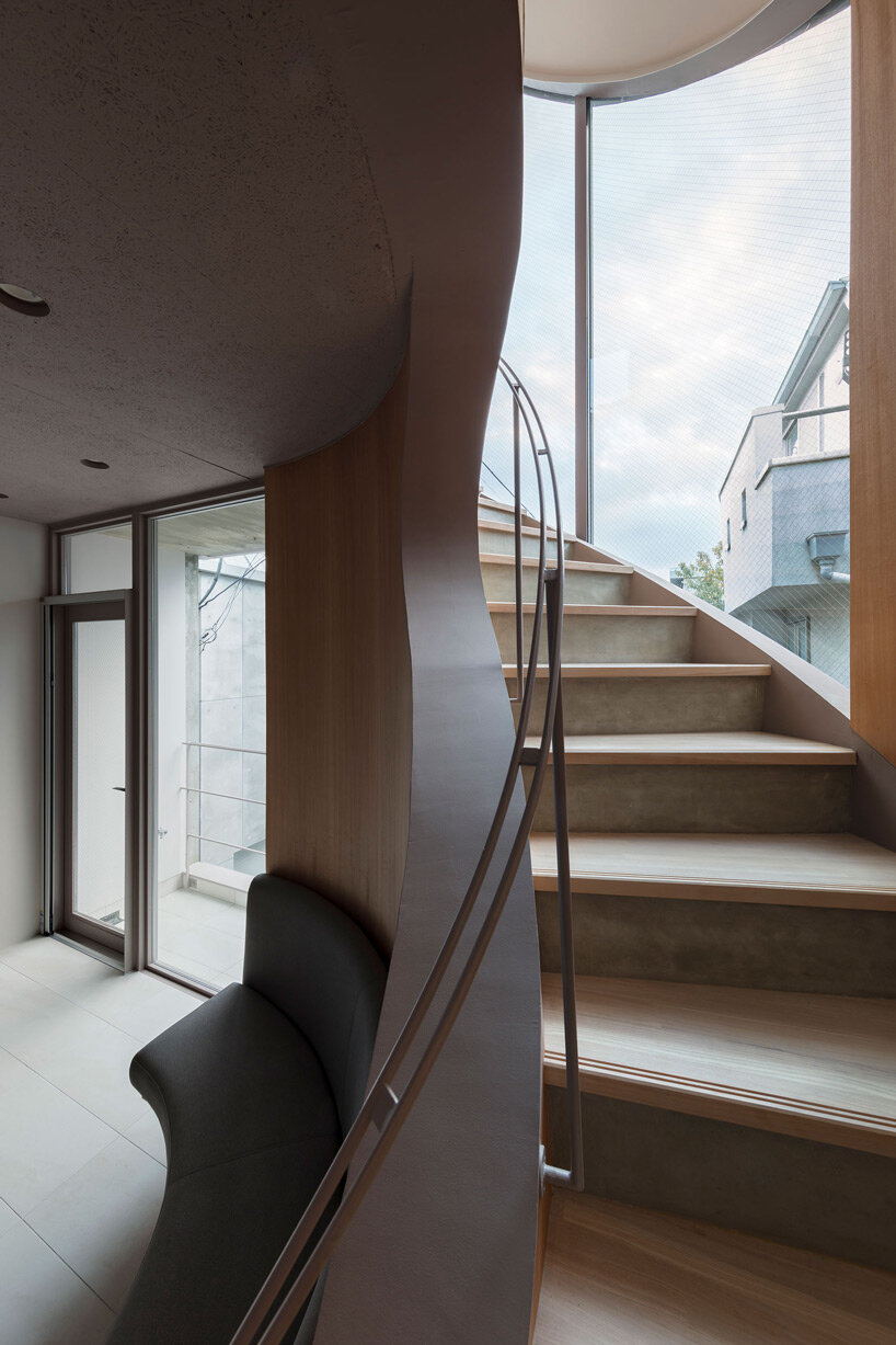 curved glass-enclosed staircase peeps out of tokyo house that 'dances in the city'