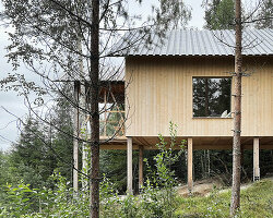 wooden cabin on stilts is perched on mountainous scenery in sweden