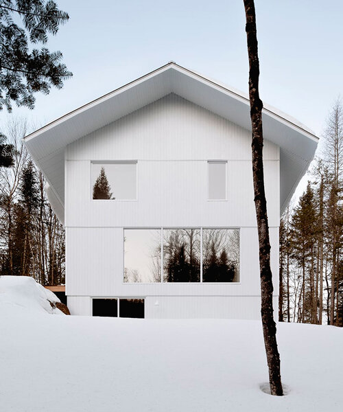 white wooden residence melds with the snowy landscape of quebec's forest