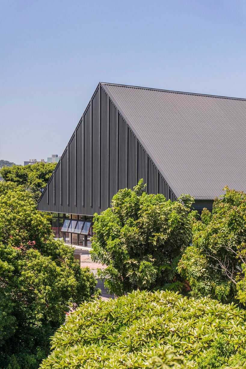  triangular metal roof crowns elevated assembly hall in taiwan school campus extension