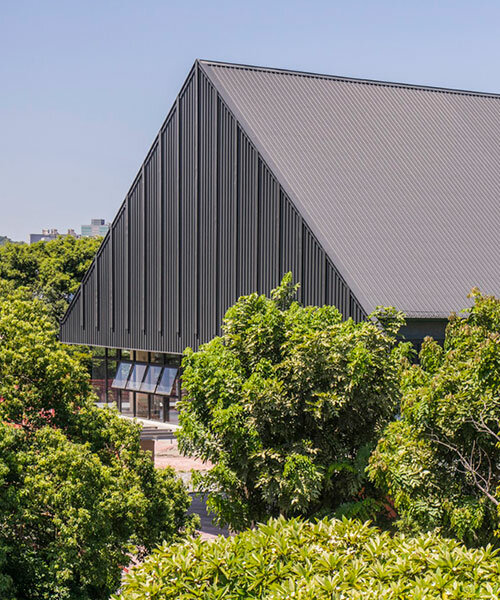triangular metal roof crowns elevated sports hall in taiwan school extension