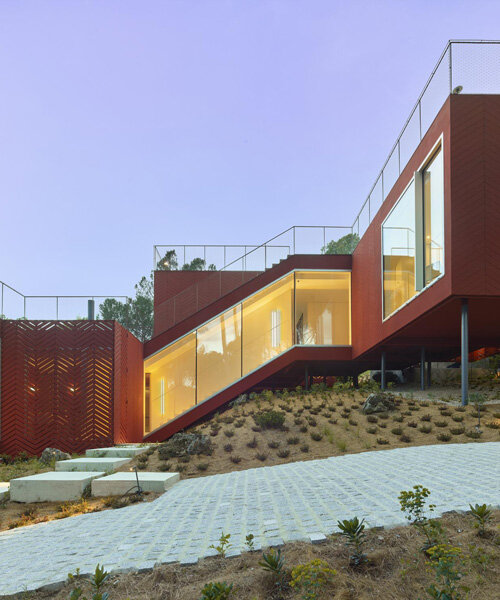 estudio entresitio's casa roja weaves down a forested hillside in rural spain