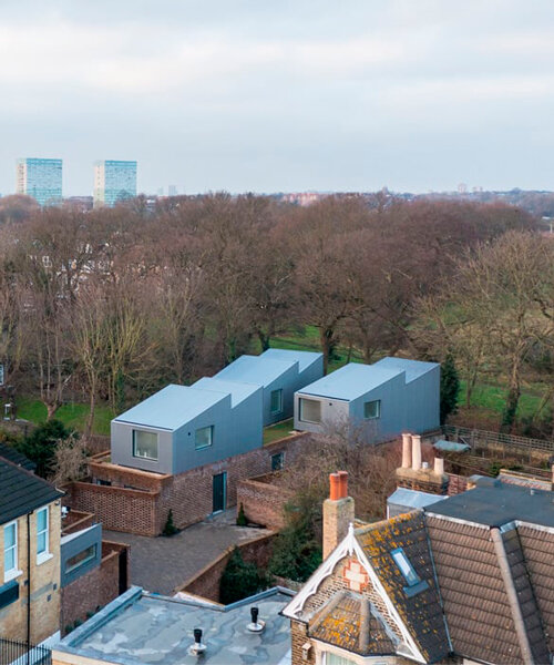 'upside-down' forest houses with sawtooth roofs rise from a brick plinth in london