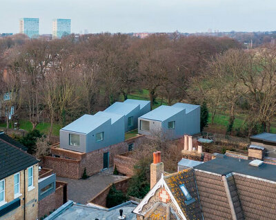 'upside-down' forest houses with sawtooth roofs rise from a brick plinth in london
