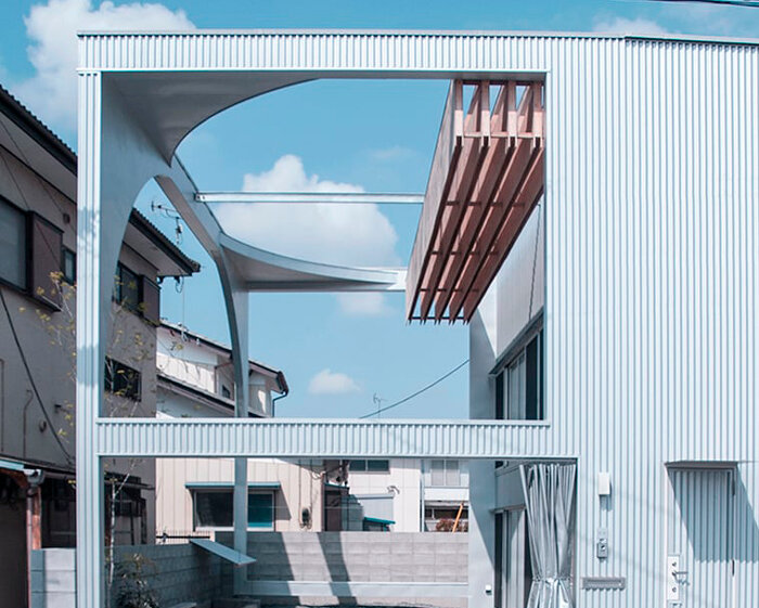 arched pergola loops over residential construction in japan covered in sheet metal