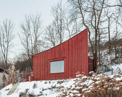 red wooden cabin's curved roof points out to the mountains of czech republic