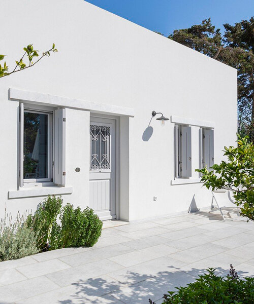 marble inlays adorn spolia house's pure white facade in greek island