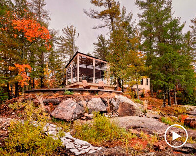 wooden cottage's jagged overhangs hover above lake landscape in canada