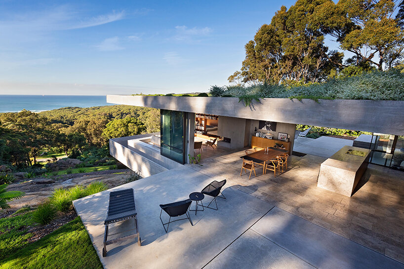 bunkeren house: half-buried volumes integrate with sloping rocky site in australian village