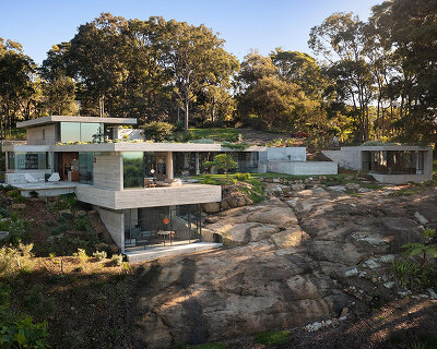 bunkeren house: half-buried volumes integrate into sloping rocky site in australian village
