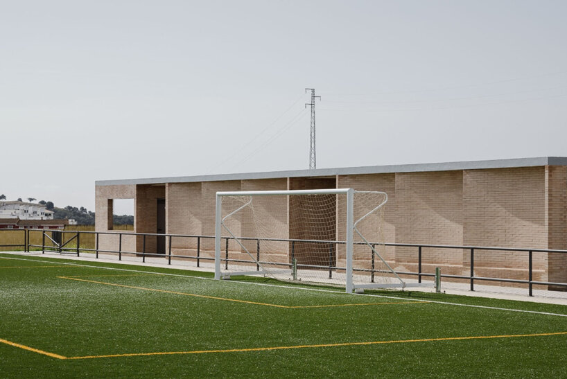 Vestuario alargado revestido de ladrillo completa un pequeño campo de fútbol en Sevilla 