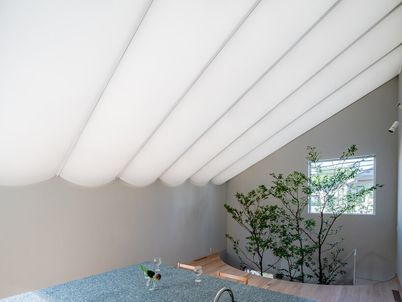 tubular membrane roof casts a soft glow over this two-story house in tokyo