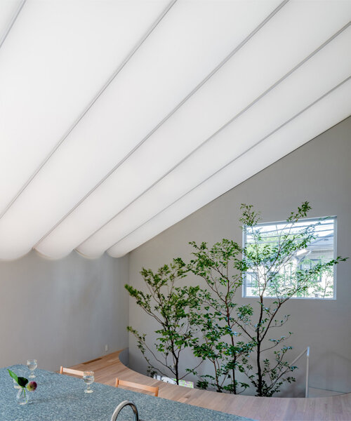 tubular membrane roof casts a soft glow over this two-story house in tokyo