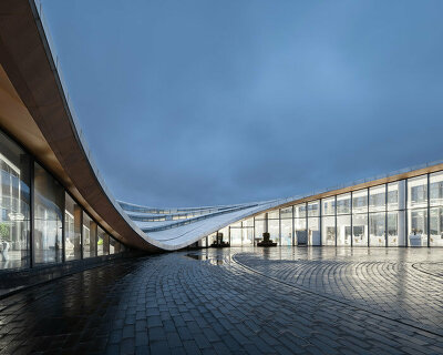 MUDA-architects' coastal haikou visitor center enclosed by a fluid, cascading rooftop