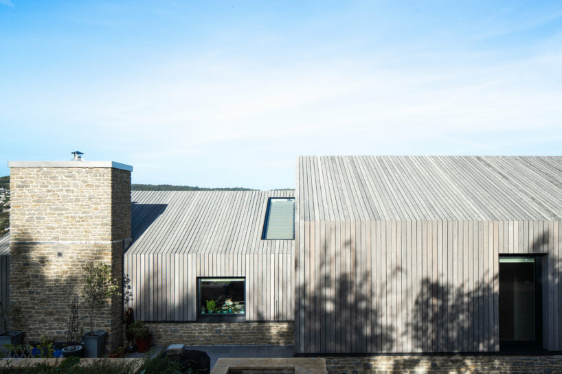 cluster of pitched timber volumes by coffey architects perches above dorset's sloping hillside