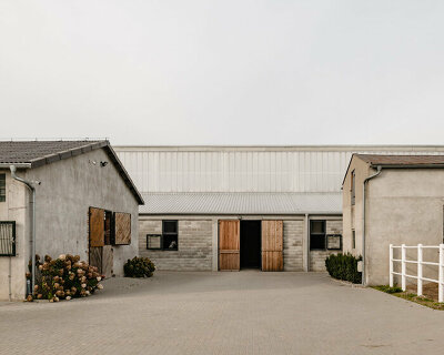 raw concrete, steel panels, and wood wrap wiercinski studio's equestrian center in poland