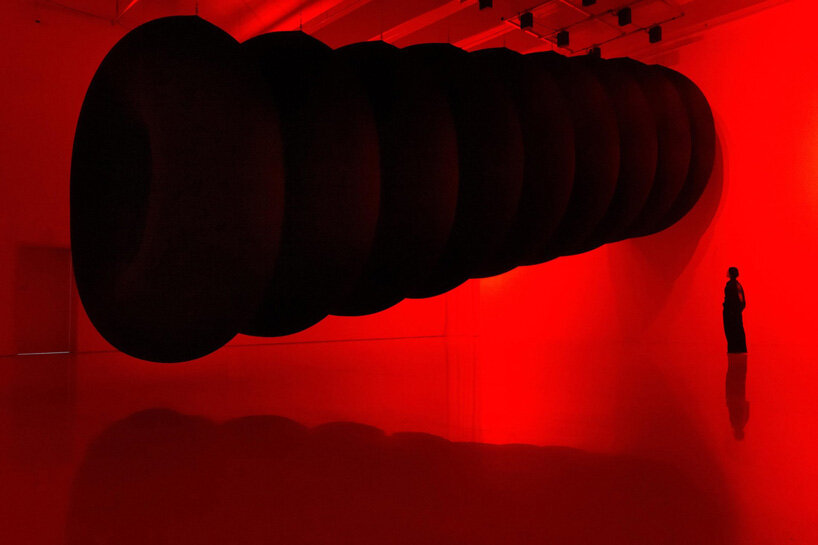 nine colossal tubes undulate and engulf visitors amid a red glow in SpY's beijing installation