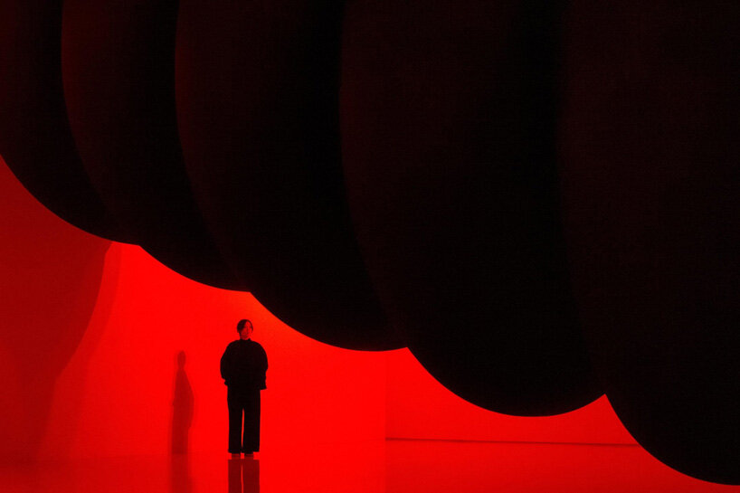 nine colossal tubes undulate and engulf visitors amid a red glow in SpY's beijing installation