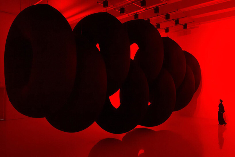 nine colossal tubes undulate and engulf visitors amid a red glow in SpY's beijing installation