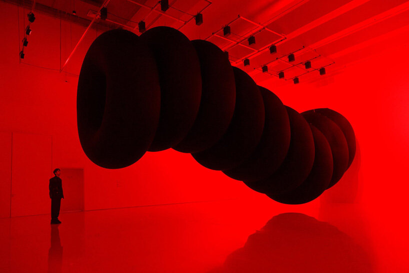 nine colossal tubes undulate and engulf visitors amid a red glow in SpY's beijing installation