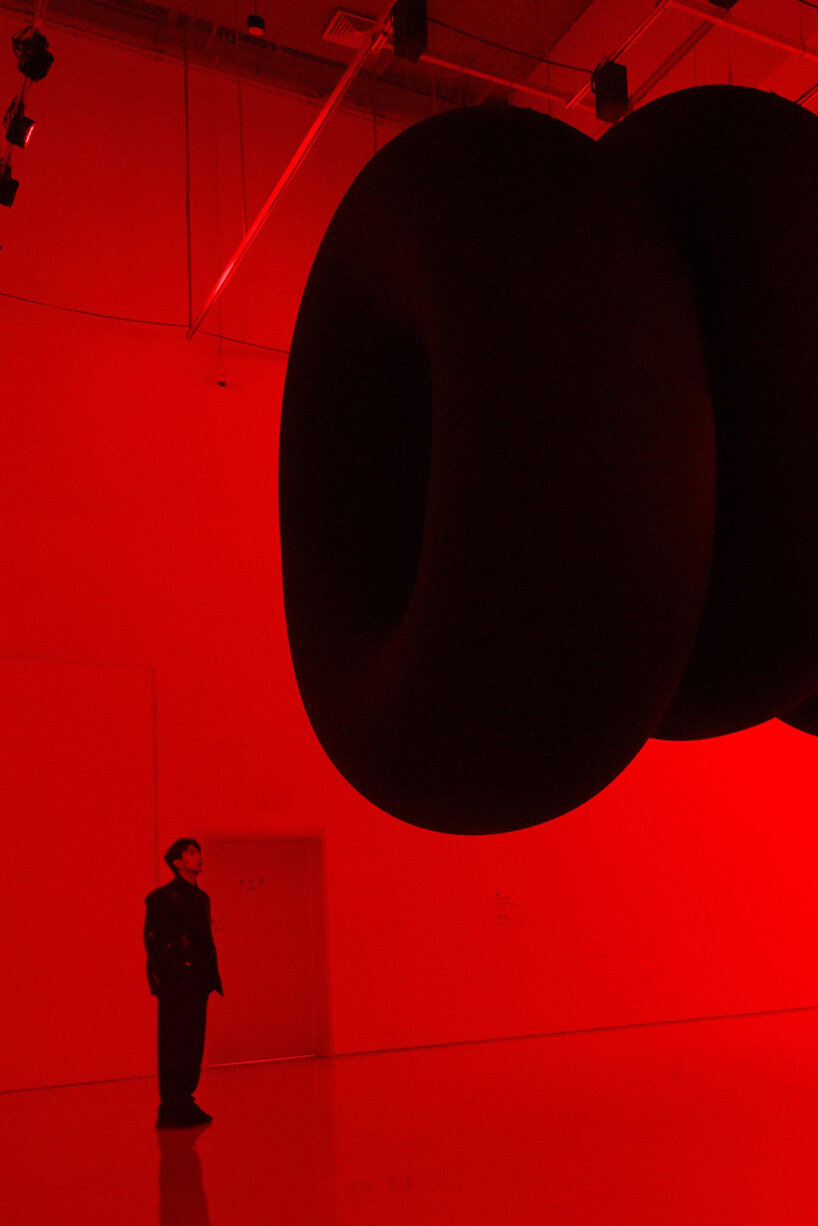 nine colossal tubes undulate and engulf visitors amid a red glow in SpY's beijing installation