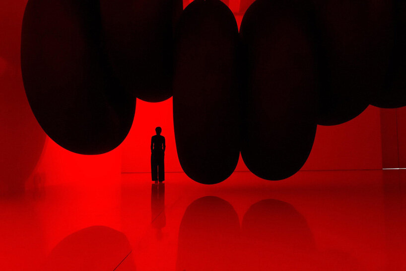 nine colossal tubes undulate and engulf visitors amid a red glow in SpY's beijing installation