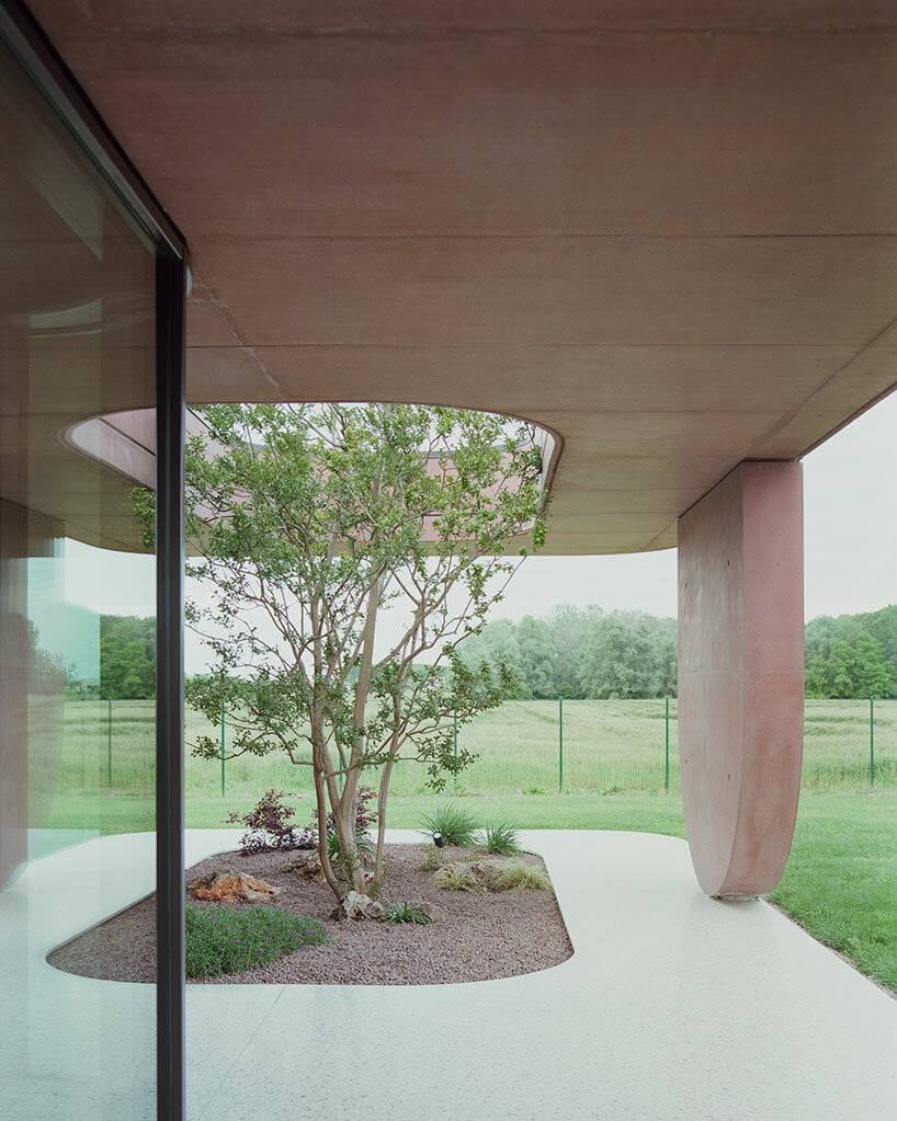MIDE architetti's pink concrete residence curves around lush vegetation in italy