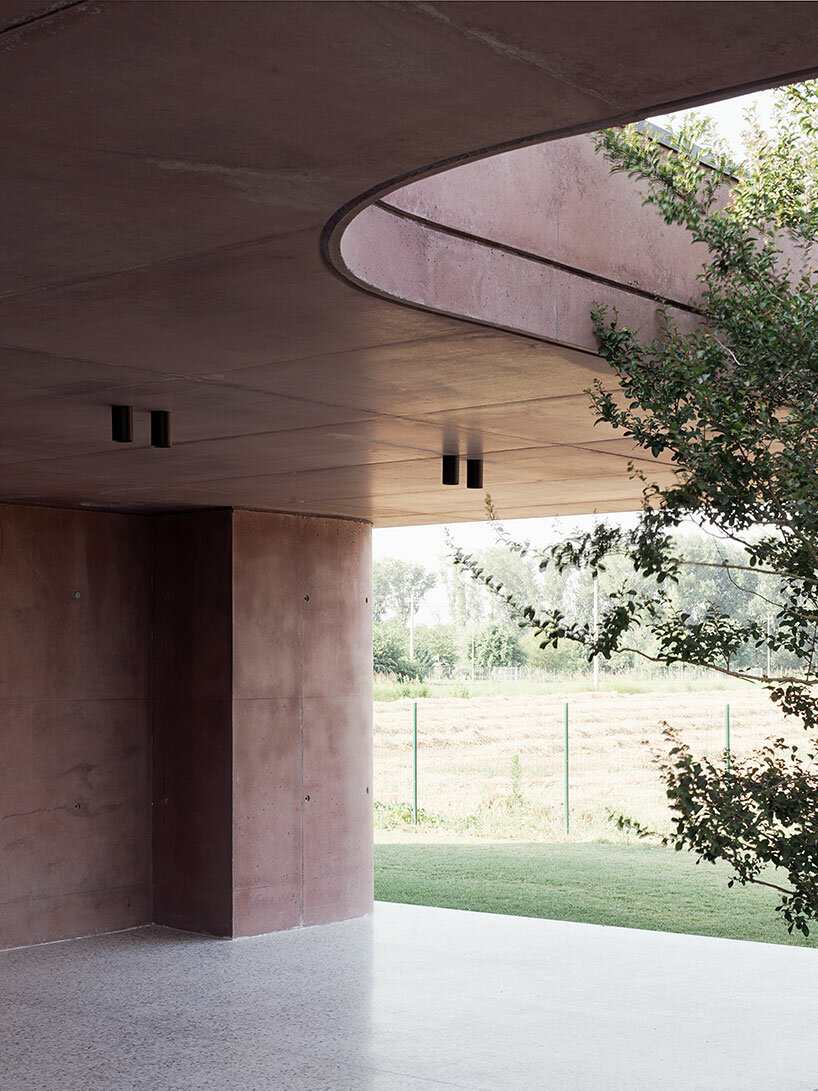 La residenza in cemento rosa di MIDE architetti si curva attorno a una rigogliosa vegetazione in Italia