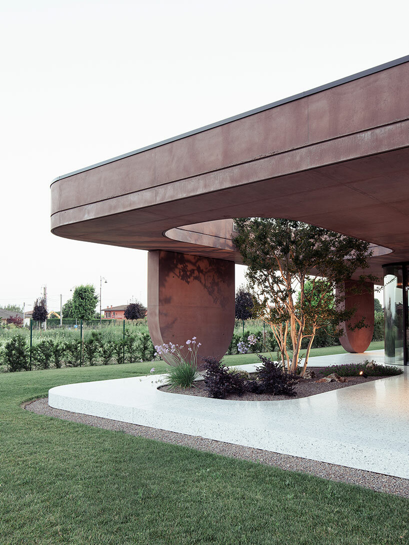 La residenza in cemento rosa di MIDE Architetti si piega attorno alla rigogliosa vegetazione in Italia