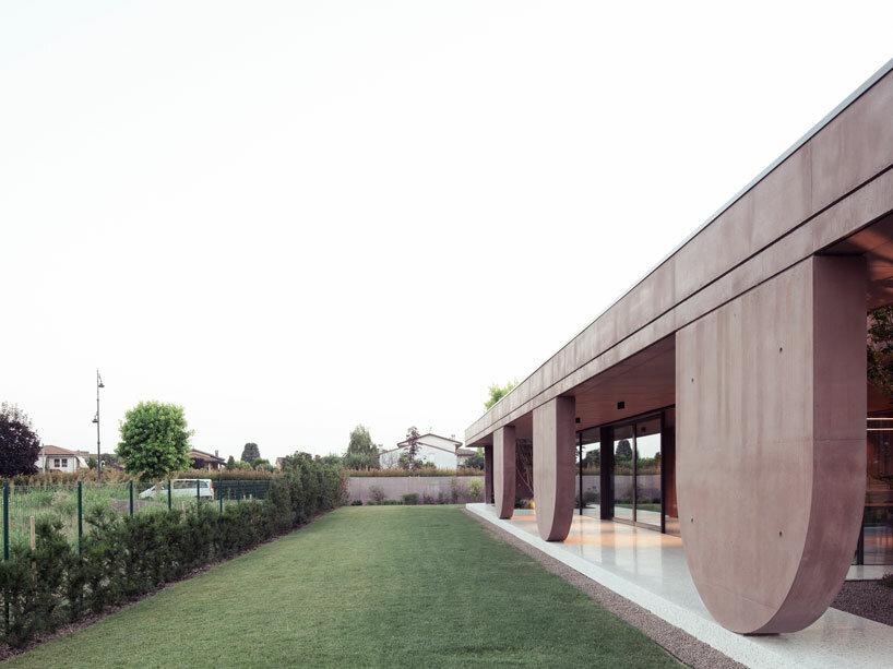 MIDE architetti's pink concrete residence curves around lush vegetation in italy