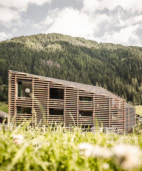 DEAR studio adapts old hay barns into modern larch log-clad hotel in italian alps