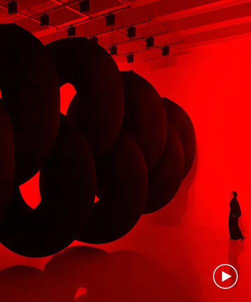 nine colossal tubes undulate and dwarf visitors amid a red glow in SpY's beijing installation