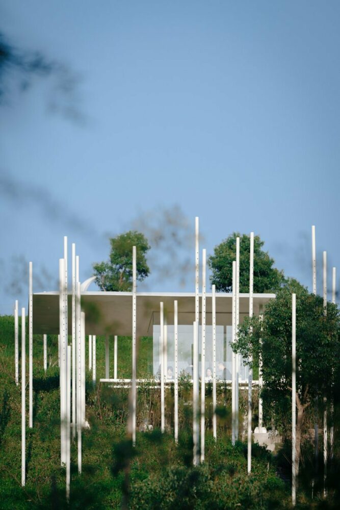 cloud tea room emerges from chinese hillside along with white steel poles infusing fog