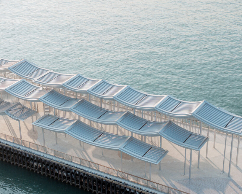 undulating canopy by new office works shelters waterfront promenade in hong kong