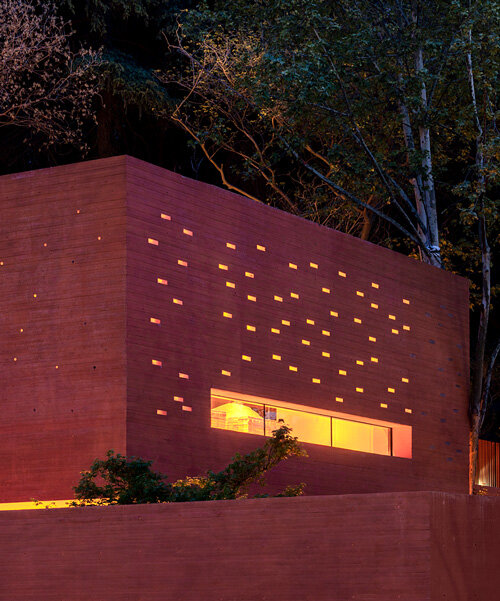 mix architecture sculpts this 'red box' exhibition center like a glowing cave