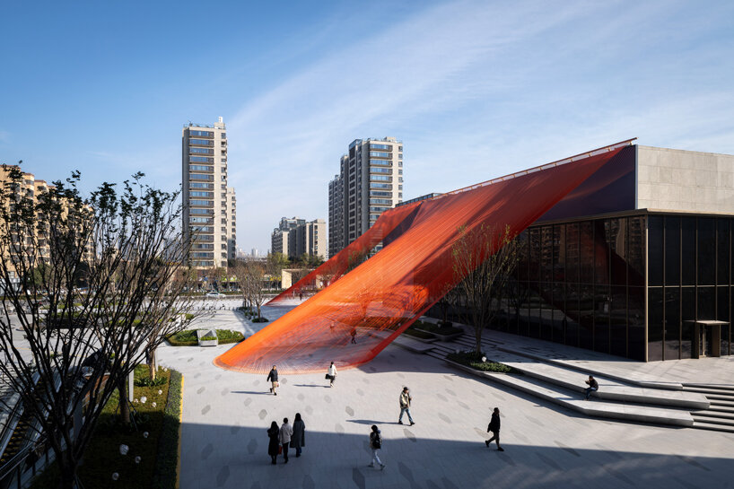 behin ha weaves temporary installation with orange mesh fabric ribbons at hangzhou complex