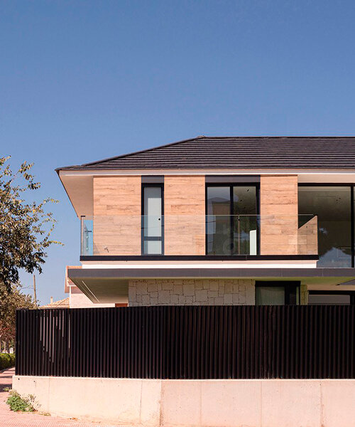 distinct black tiling and hewn stone clad two-story residence in spain