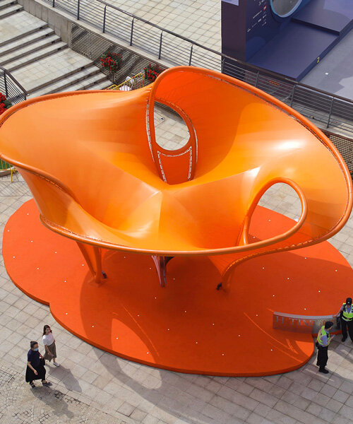 orange tensile membrane attaches to curved steel pipes shaping eddy pavilion in shanghai