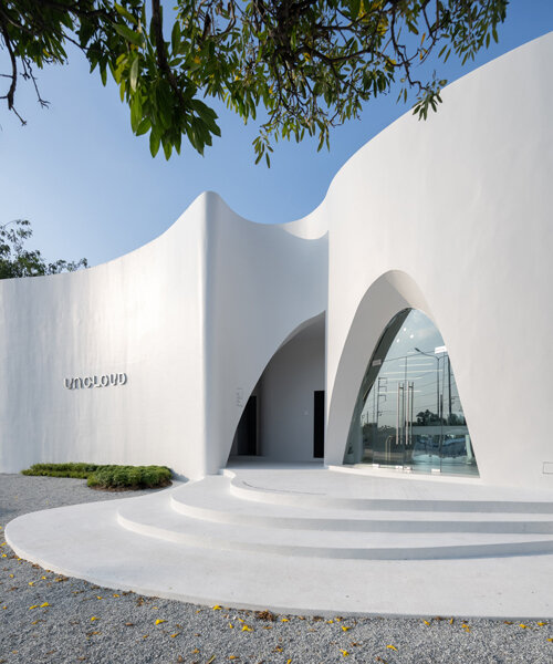 uncloud coffee's arching white structure integrates smoothly into its surroundings in thailand