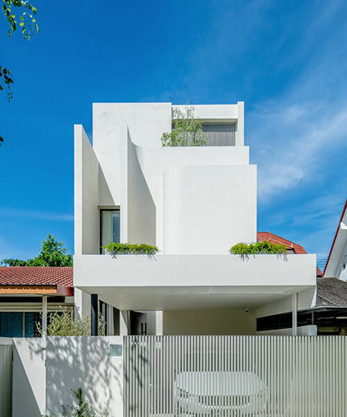 fluid facade envelops all-white monolithic curlicue house in singapore