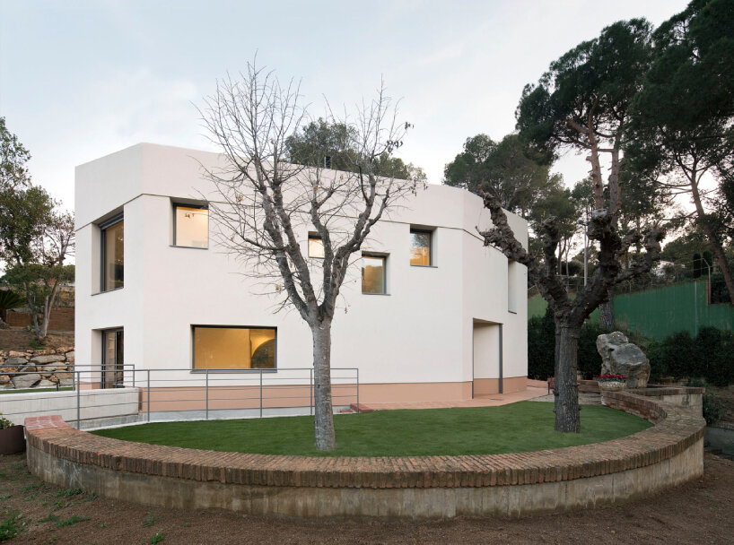 La residencia escultórica de España aparece como una masa completamente blanca entre altos pinos.
