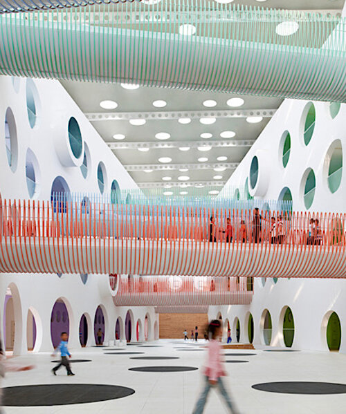 twelve colorful bridges suspend over zigzag elementary school's atrium by SAKO architects