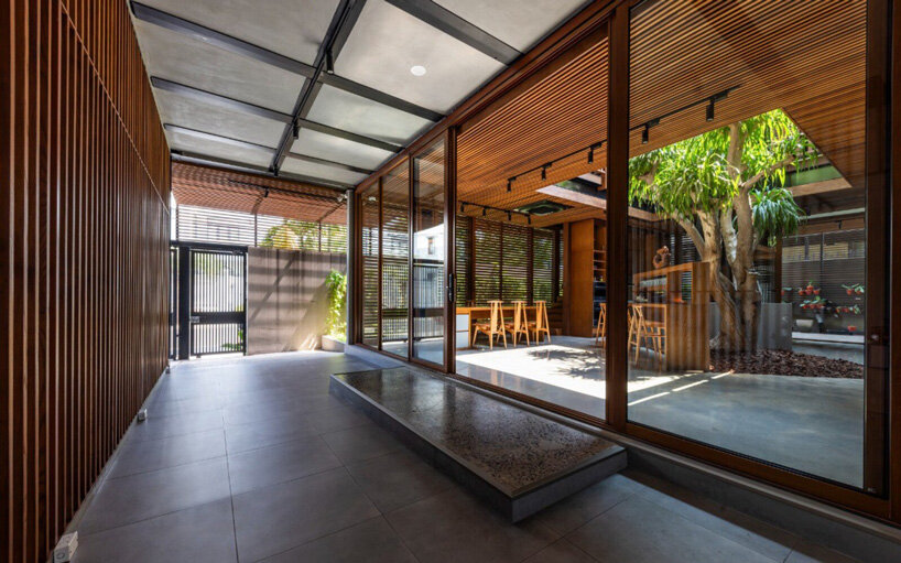 a+ architects' ecobreeze house self-breaths through wooden double-skin facade in vietnam