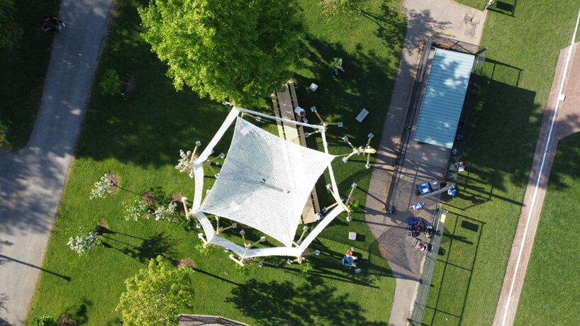 vanishing community room by alsar atelier uses tree stakes and textile canopies for shading